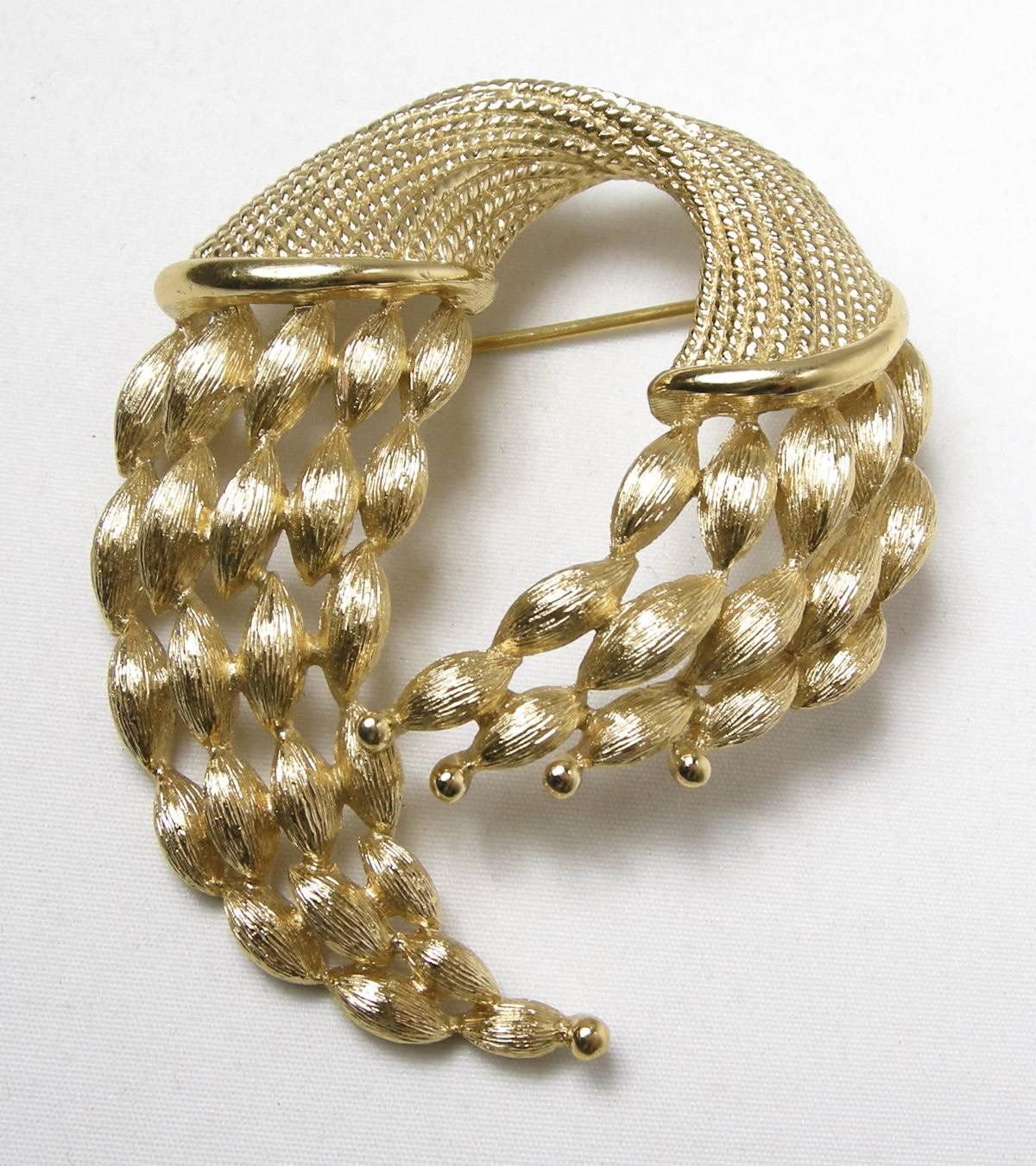 This Monet brooch has a slightly domed golden twist rope design and measures 2-1/2” x 2-1/4”.  The earrings are round button earrings with a ribbed design. They measure 1” x 1”. This set is signed “Monet” and is in excellent condition.