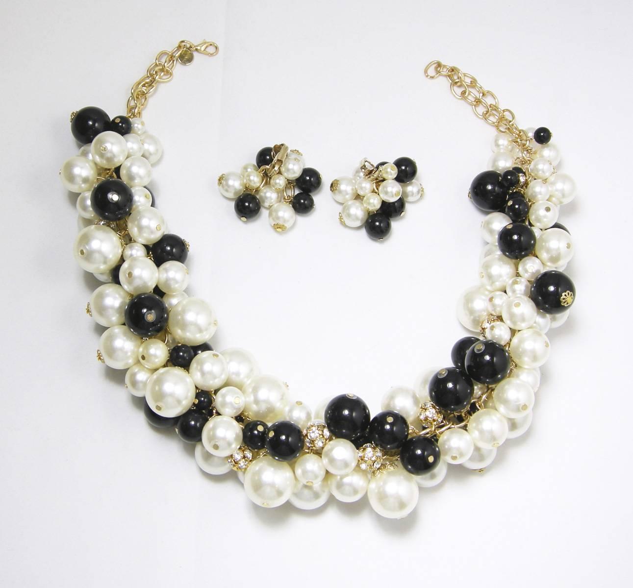 This jumbo black & white faux pearl necklace makes a classy accessory!  The pearls are multi sized and have round crystal beads that are set in a gold tone setting. The necklace measures 20” x 2” at its widest point. The earrings measure 2” x