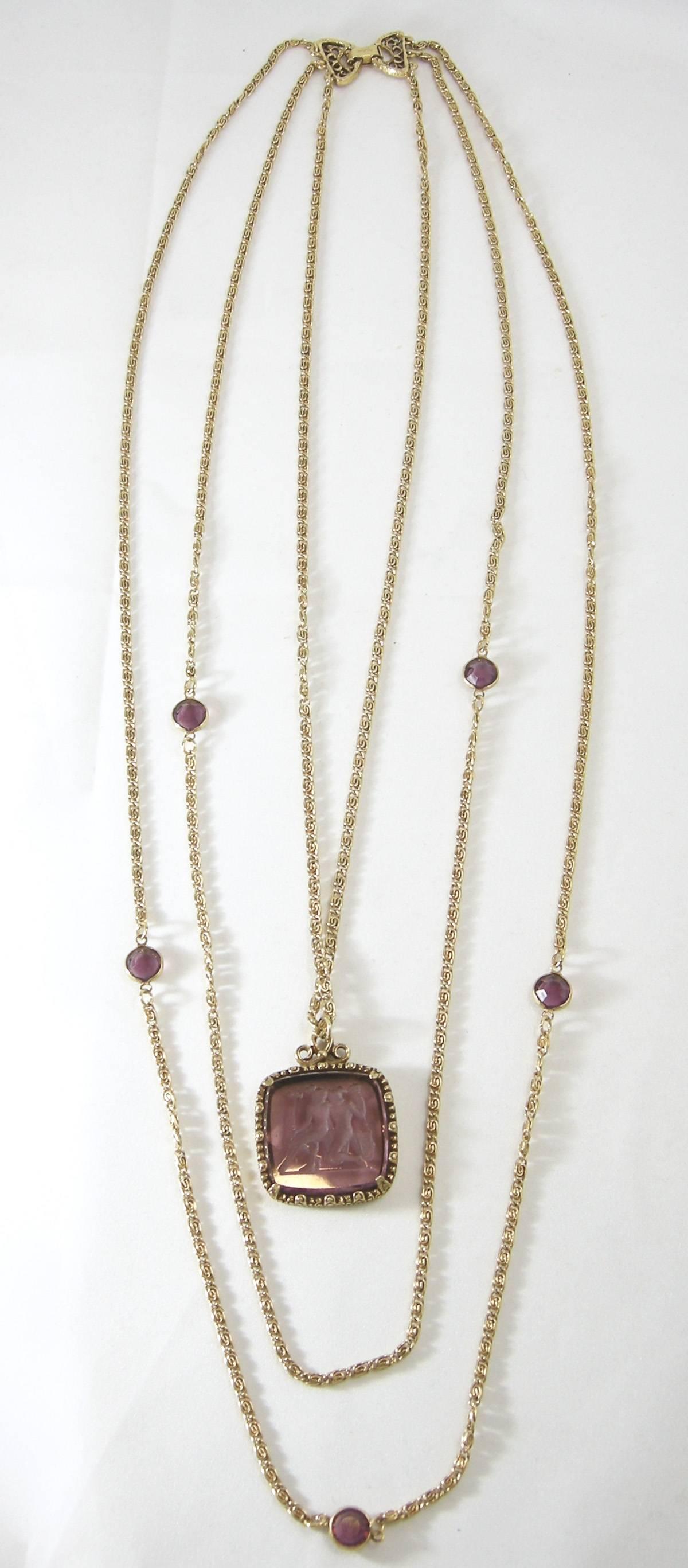This Goldette 1960s necklace is one of the most sought-after necklaces. It has a purple Intaglio pendant in the middle with two more chains interspersed with purple glass accents.  The longest chain is 25” and the pendant in the middle is 1-1/4”. 