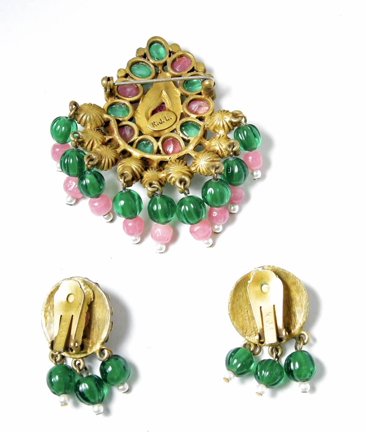 This is a rare and collectible Kenneth Jay Lane brooch and clip earrings set from the 1960s.  It is designed with pink and green poured glass with dangling faux pearls and green and pink poured glass beads at the bottom.  It is set in an antique