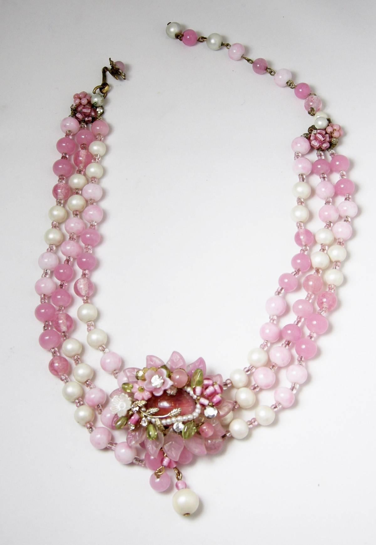 This beautiful 1950s Miriam Haskell necklace has 3 rows of pink glass beads and faux pearls leading down to a gorgeous floral centerpiece that overlaps the two bottom rows.  The necklace is 16” long.  The centerpiece is 2” wide and 2-1/2” long, with