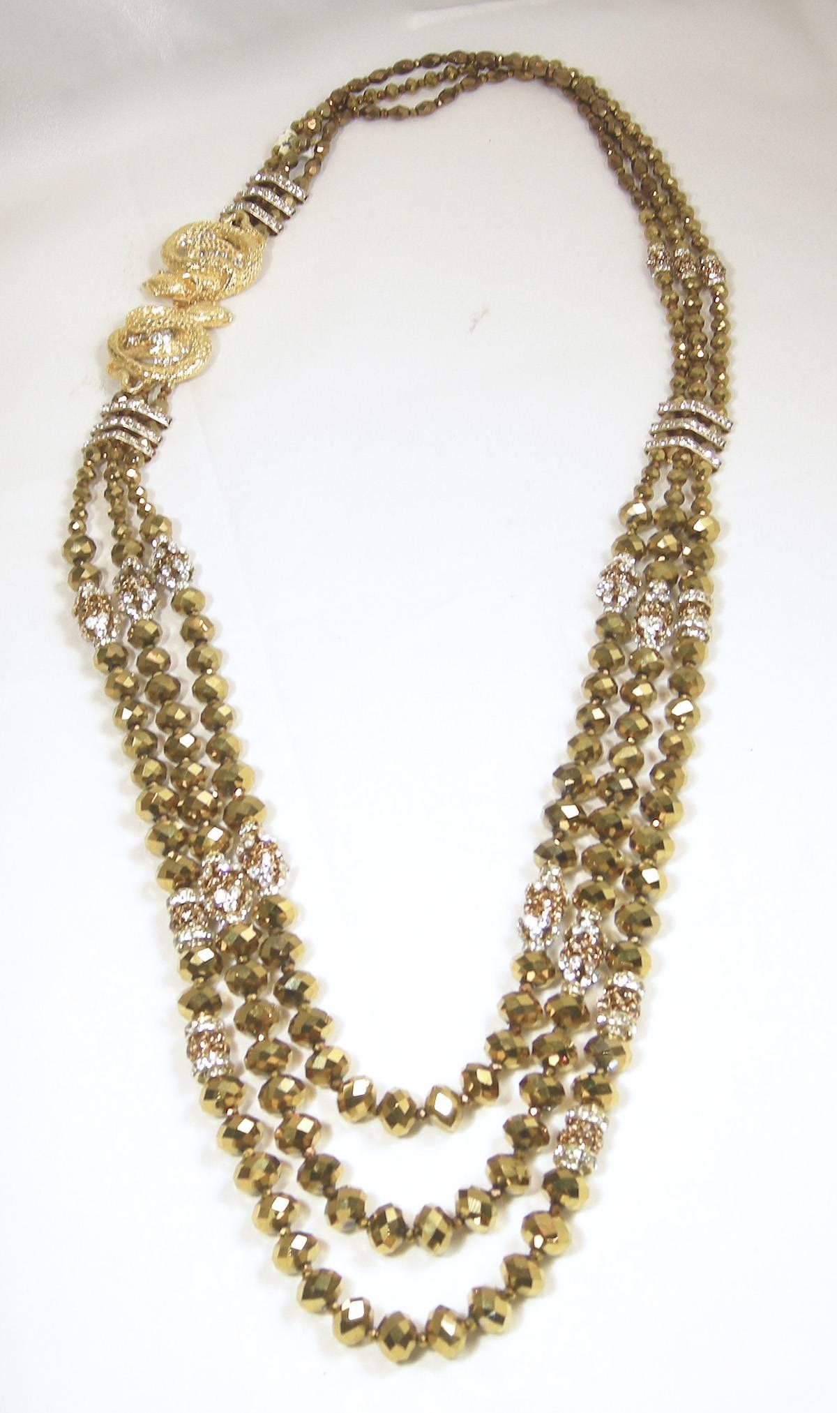 This one-of-kind Robert Sorrell necklace is very special.  It has 3 strands of golden glass beads with crystal bars connecting the rows of beads. The crystal snake has a slide-in clasp enabling you to wear this necklace with the snake on the side. 