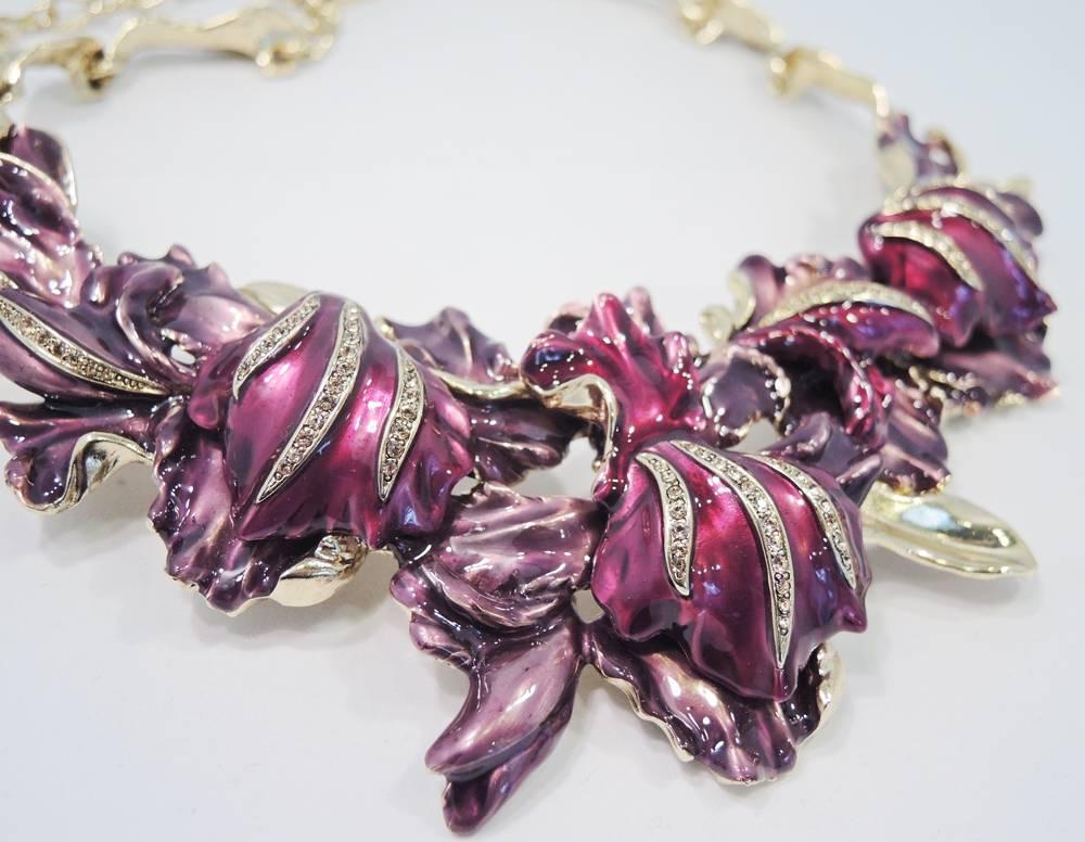 This Oscar De La Renta necklace features a floral orchid design with different shades of lavender and purple enameling accentuated with rhinestones.  In excellent condition, it is set in a gold tone setting and has a lobster clasp and measures 19” x