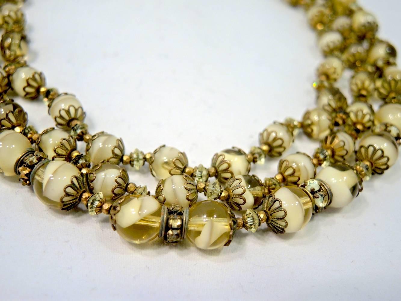 This vintage signed Miriam Haskell 3-strand necklace features light yellow and cream color glass beads with crystal spacers in a gold-tone setting.  This necklace measures 16” x 1” with a slide in clasp.  It is signed “Miriam Haskell” and is in