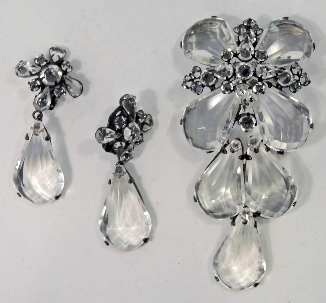 This vintage famous signed Schreiner set features a faceted Lucite floral design with tear drops extended downward…in a Japanned metal finish.  The pin measures 4-1/8” x 2”.   The matching clip teardrop earrings measure 2-1/2” x 1” and is signed