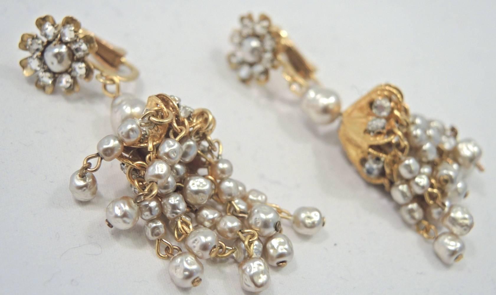 These vintage signed Miriam Haskell earrings features faux pearls hanging like a flowing chandelier with crystal accents in a gold-tone setting.  In excellent condition, these clip earrings measure 2” x 3/4” and are signed “Miriam Haskell”.