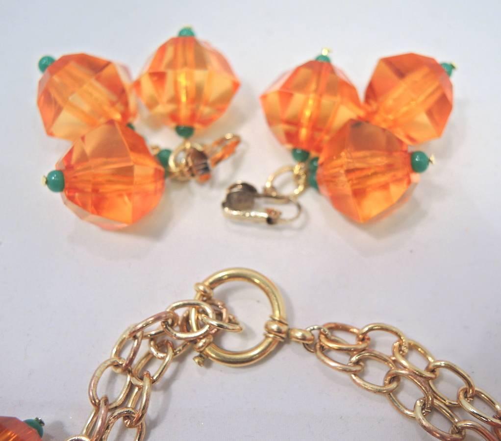 This one-of-a-kind set by Anka features vintage chunky orange and green Lucite beads in a gold tone setting.  The necklace measures 18” x 2” and has spring closure.  The matching clip earrings measure 2-1/2” x 1-3/4”.  It is signed “Anka” and is in