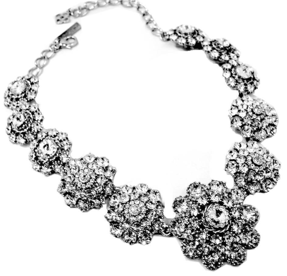 This is a beautifully designed crystal necklace by Oscar de la Renta that floats lightly along the neckline. It measures 21”x 2” at its widest point. It is set in a silver tone metal finish and has a lobster clasp. It is signed “Oscar De La Renta”