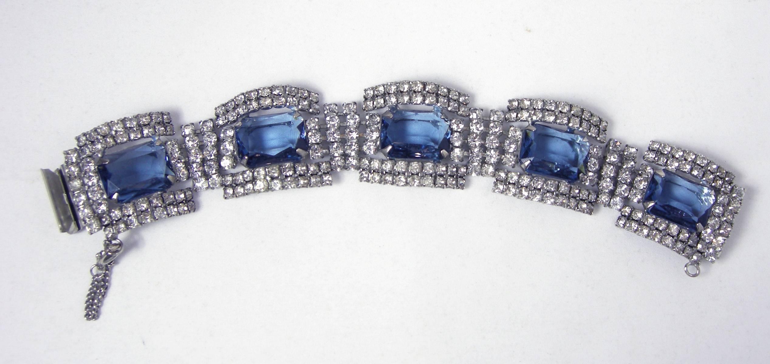 This stunning Deco bracelet features five large sized faux blue sapphire rhinestones surrounded by clear rhinestones in a silver tone setting. The bracelet measures 7-1/2” x 1-1/4”. It has a slide in clasp and is in excellent condition.