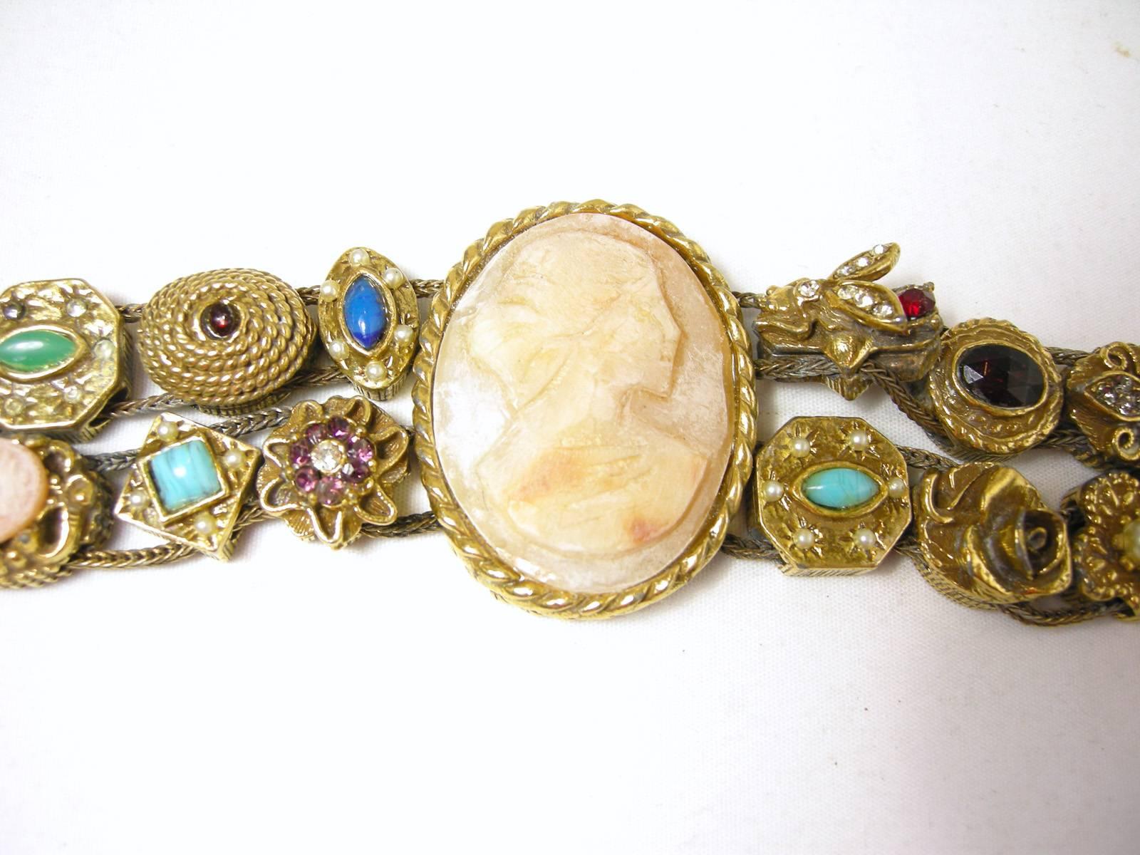 It is so rare to find a Goldette slide bracelet, but here it is. It has double strands of metal ropes that is intricately detailed and features many different types of colorful charms leading to the center cameo. It is set in a gold tone setting and