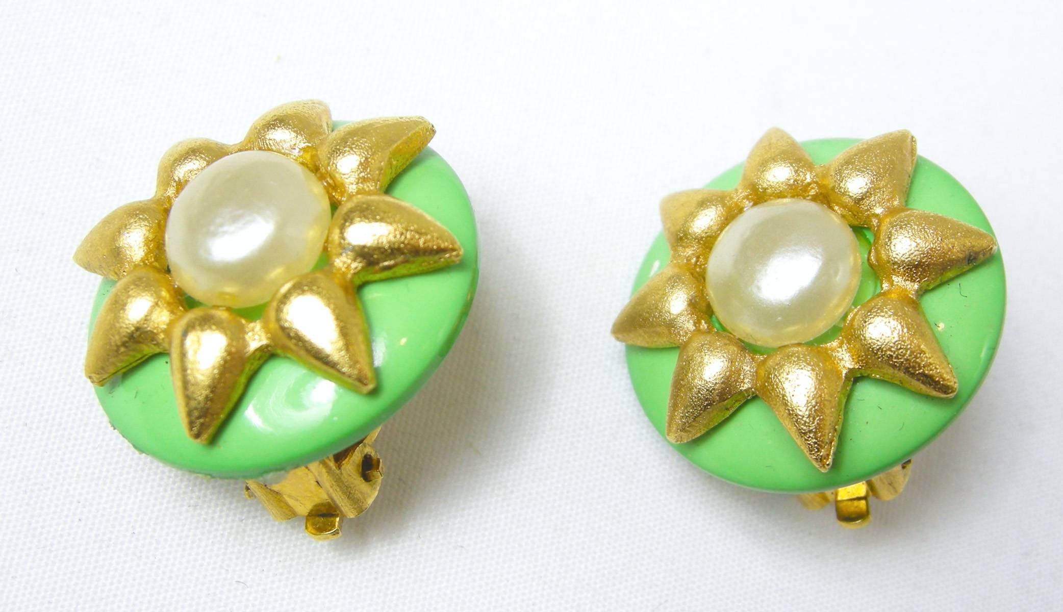 These Chanel green enamel round earrings feature a sunflower setting in a gold tone metal finish with a faux pearl in the center. They measure 1” x 1”.  They are signed “Chanel 95C” and “Made in France”. They are in excellent condition.