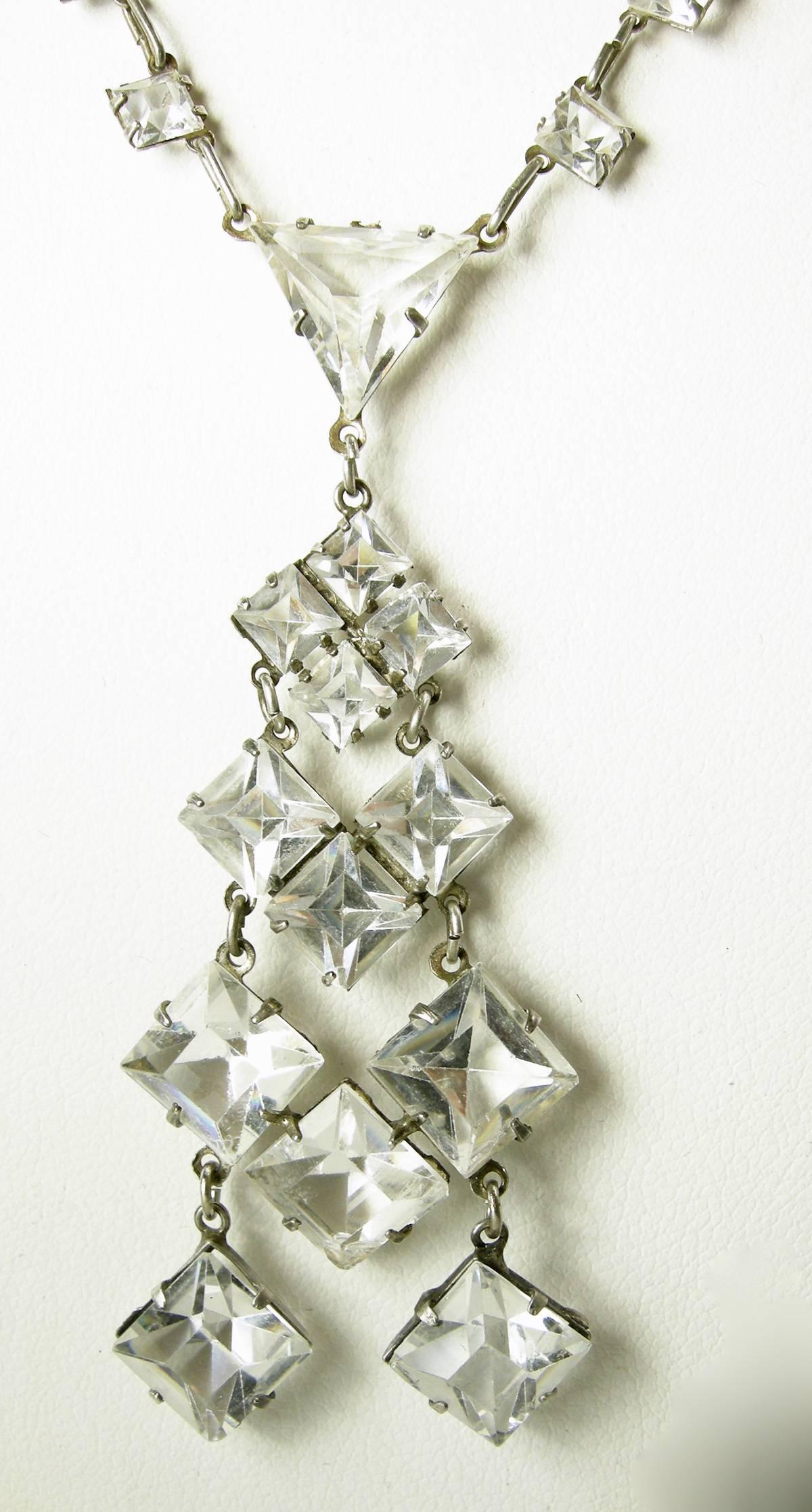 This stunning 1920s Deco crystal necklace is made with geometrical square crystals dangling from a sterling silver necklace accented with crystals all the way to the centerpiece.  The necklace measures 17” and the centerpiece is 2-1/2”. It is signed