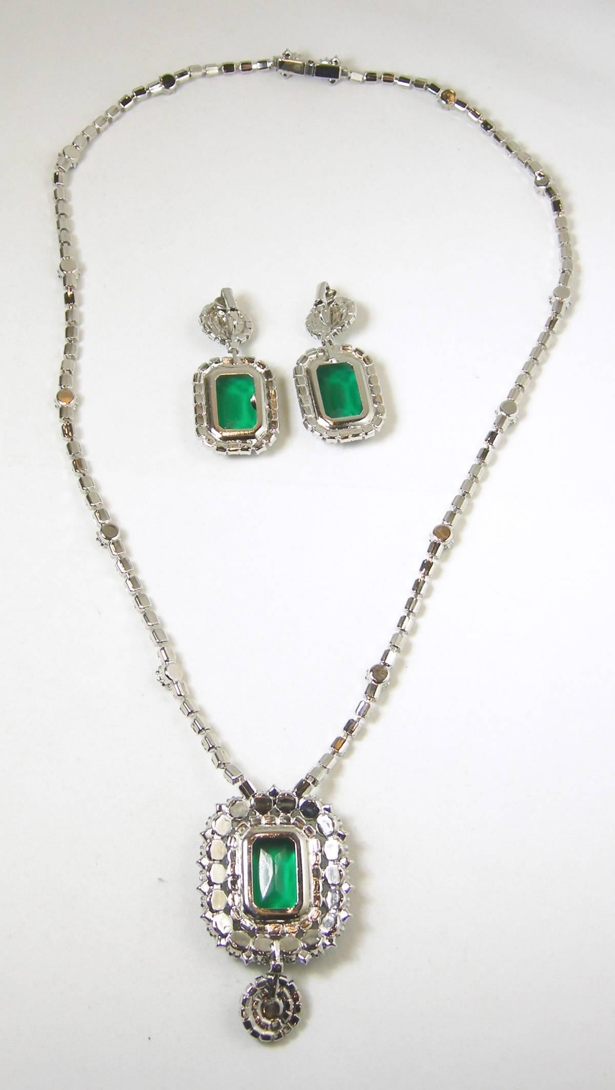 This is an absolutely stunning collection. It features a Faux emerald green and clear rhinestone statement necklace. The pendant necklace features a large emerald cut glass rhinestone that has brilliantly clear sparkly rhinestones surrounding and
