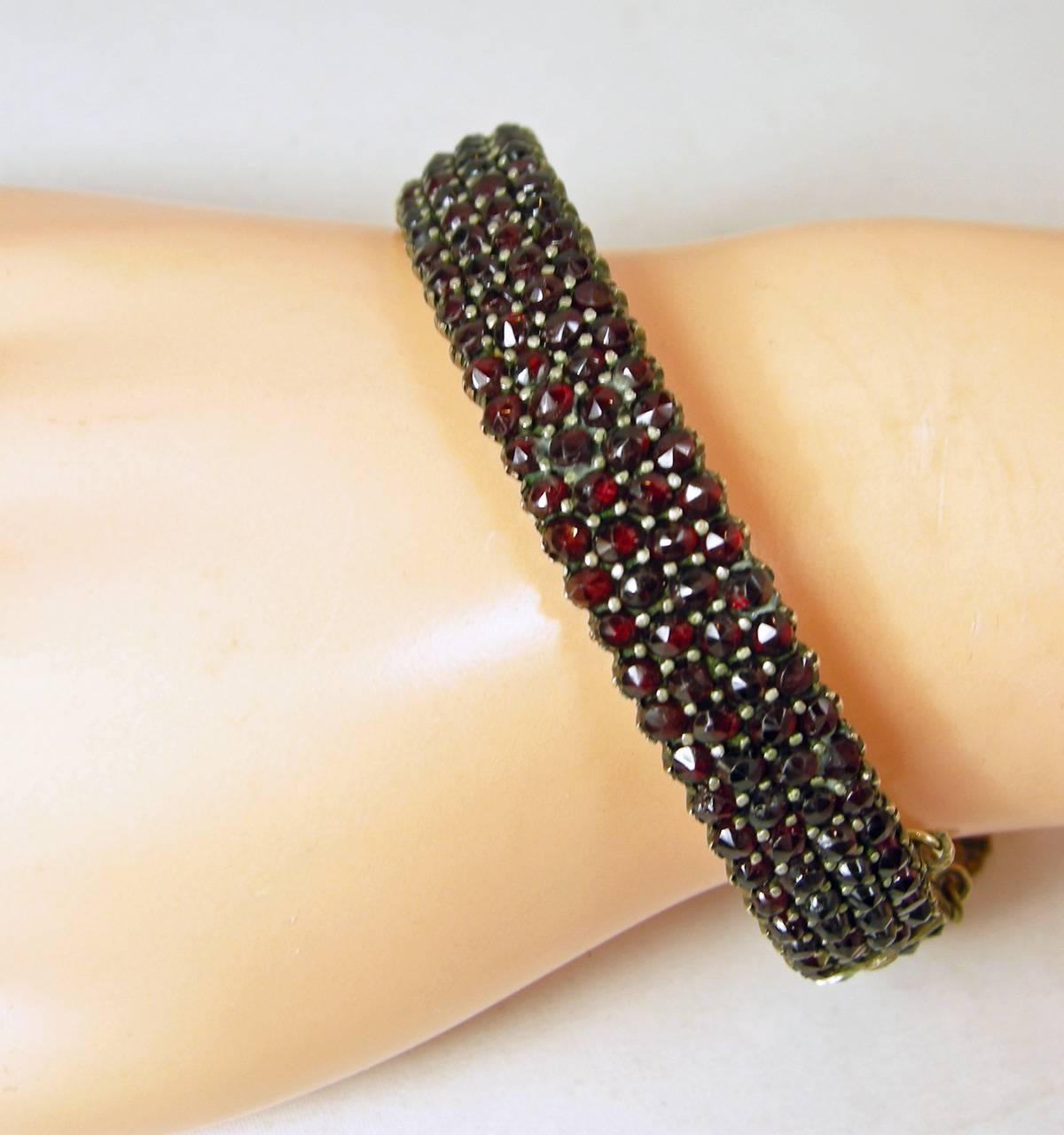 This vintage cuff bracelet has a pave of garnets that are prong set going around the entire bracelet. The bracelet is made of sterling silver over a gold vermeil. It has a slide in clasp with a safety chain. The bracelet measures 8” x 1/2” and is in