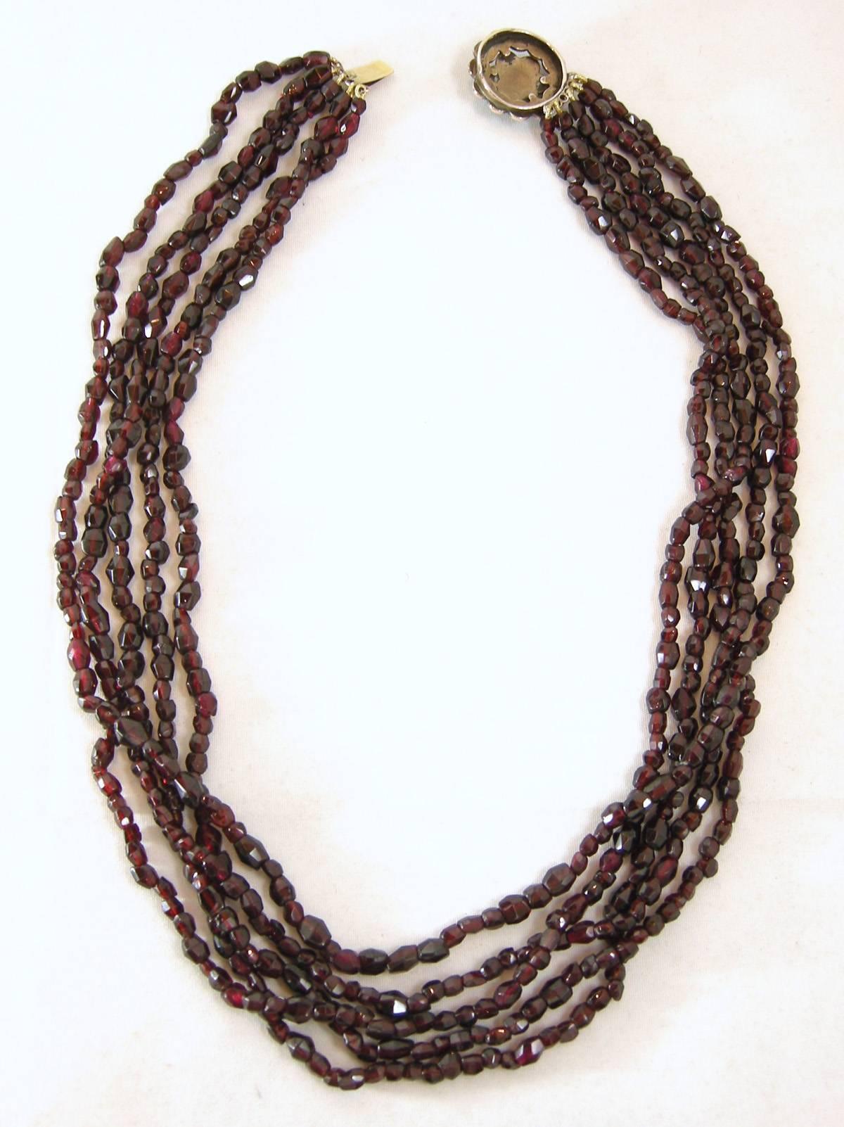This vintage Victorian five strand choker is made of deep crimson garnet beads . It is accented with a flower in the center.  It is made of sterling silver over a gold vermeil and has a slide in clasp. The necklace measures 16” x 3/8”.  It is in
