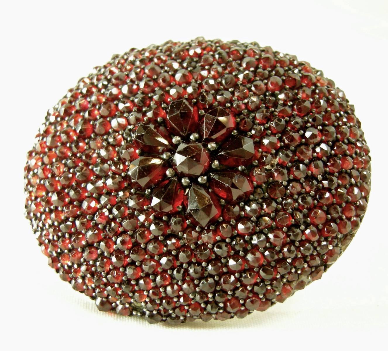This fabulous Edwardian oval brooch has vibrant pave of garnets. It features a floral design in the center. It is made of sterling silver over a gold vermeil and measures 1-3/8” x 1-1/2” and is in excellent condition.