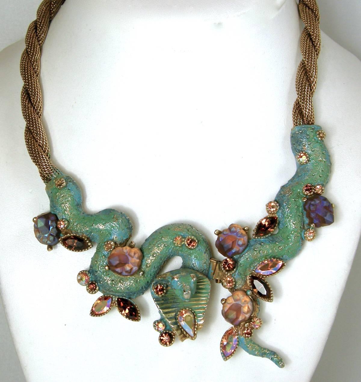 This is a rare and famous HAR vintage cobra necklace. It has a twisted gold tone chain leading down to the cobra centerpiece. The cobra has HAR’s famous Aurora Borealis stones on green shimmering enameling.  It has a prong set lava stones. The