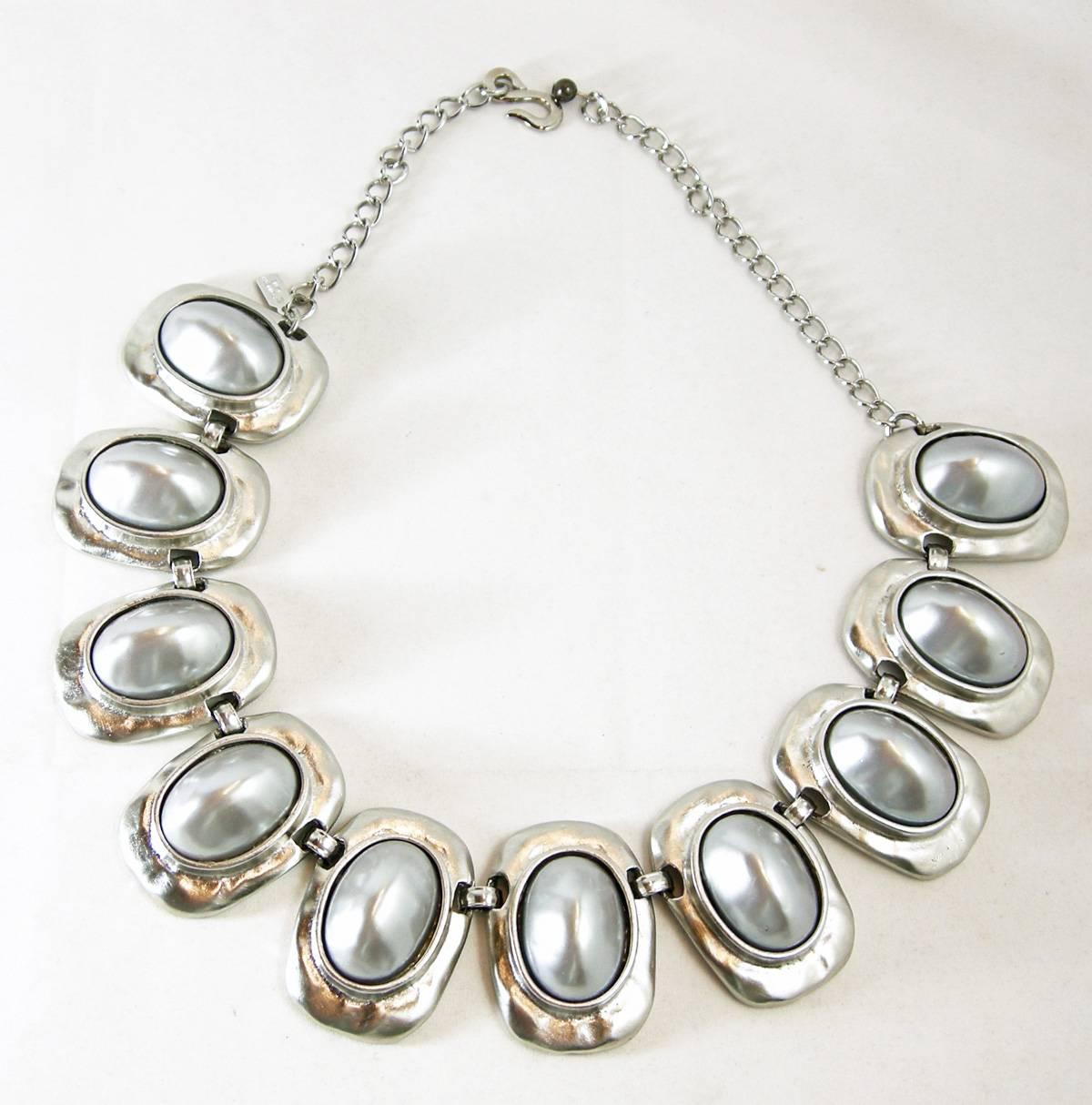 This Kenneth Jay Lane link necklace has ten links with simulated grey pearl cabochons. It is set in a silver tone setting with has a lobster clasp and measures 20” x 1-1/2”.  It is signed “Kenneth Lane” and it is in excellent condition.