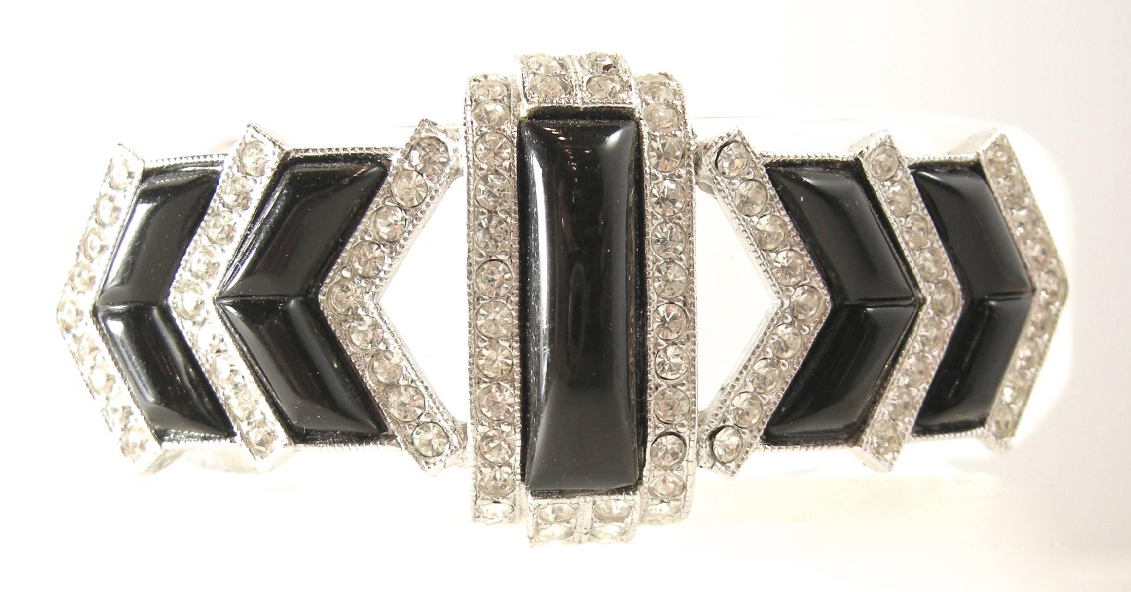 This Lucite hinged cuff bracelet has an art deco feel to it. It has faux onyx and is adorned with vibrant rhinestones.  It can fit a wrist size up to 8” and measures 9