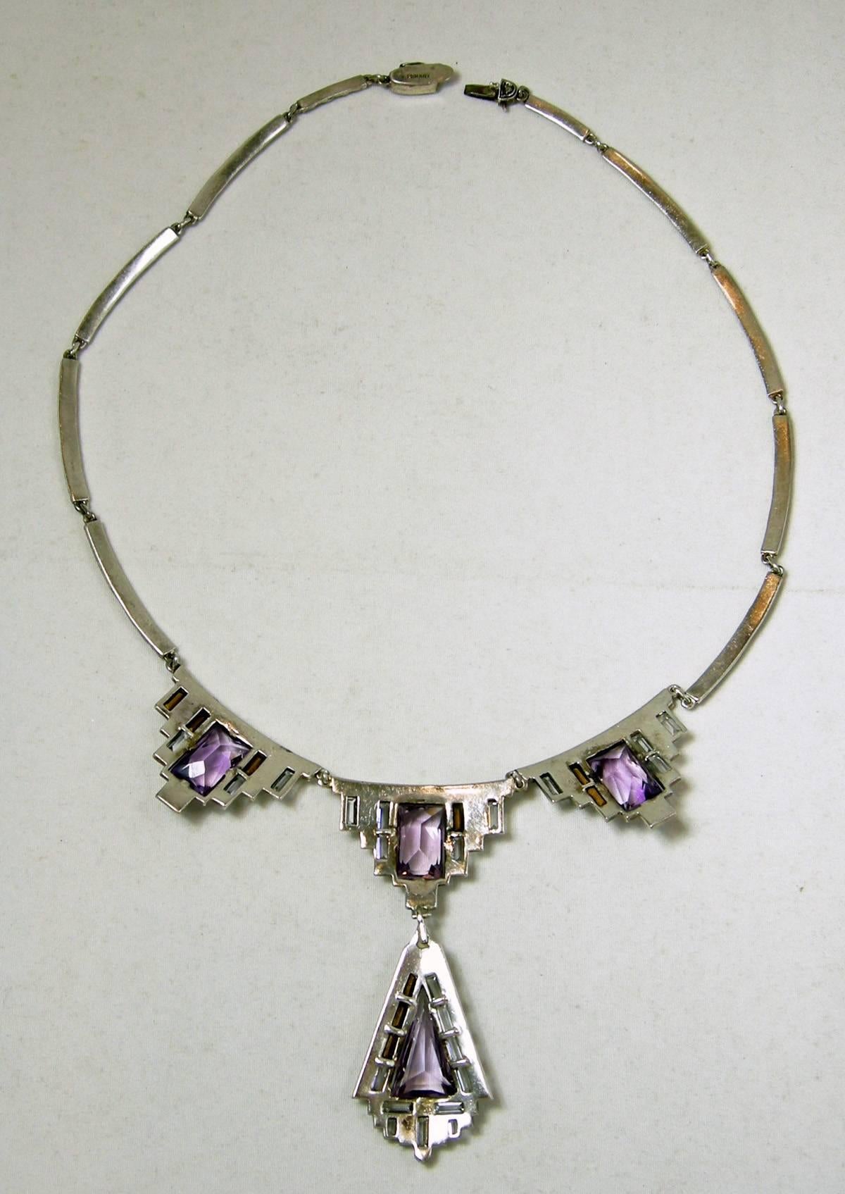 This highly collectible early German vintage necklace has triangular and square shaped amethyst stones that are prong set. The pendants have beautiful baguette stones and marcasites all around it. The necklace is made of sterling silver and measures