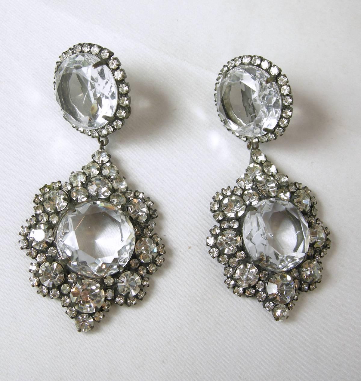 These are a pair of rare1960’s “K.J.L.” crystal drop earrings that are stunning! They feature a bold large centered clear crystal that will light up your face when you wear them. The center stone is surrounded by vibrant, floral crystal clusters.