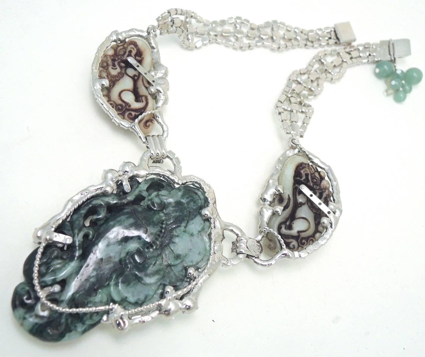 This is a Robert Sorrell “one of a kind” masterpiece.  The necklace features a large, heavily carved faux jade center & side-pieces that are framed by vibrant clear crystals. The centerpiece measures 3-1/2” x 2-1/2”.  The sides pieces on each side