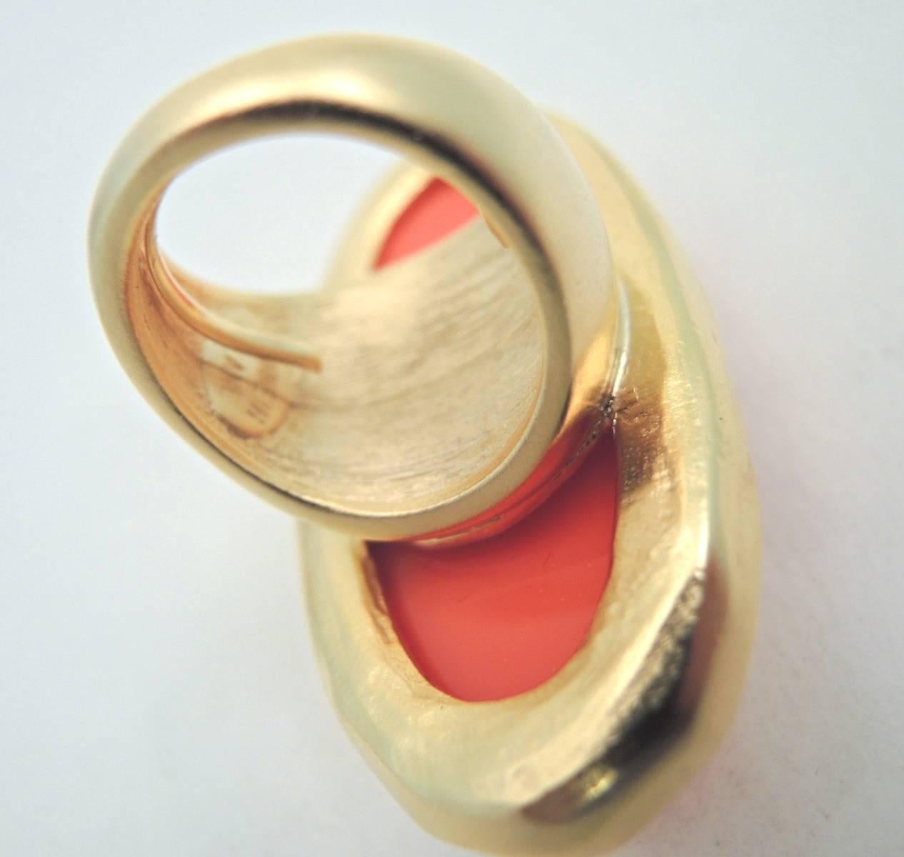 This massive Kenneth Jay Lane ring has an oval shaped faceted faux coral resin stone. It is in a gold tone setting and the large stone measures 2-1/8” x 1-1/8”. It is adjustable up to a size 7 and is signed “Kenneth Lane”. It is in excellent