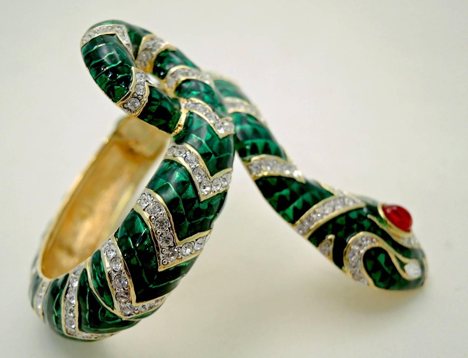 This is one of Kenneth Jay Lane’s gorgeous serpent bracelets that is made with green enamel and beautiful clear crystals. It has a large red crystal on the top of the head and teardrop shaped clear crystal eyes. It measures 8” x 3-3/8” at the widest