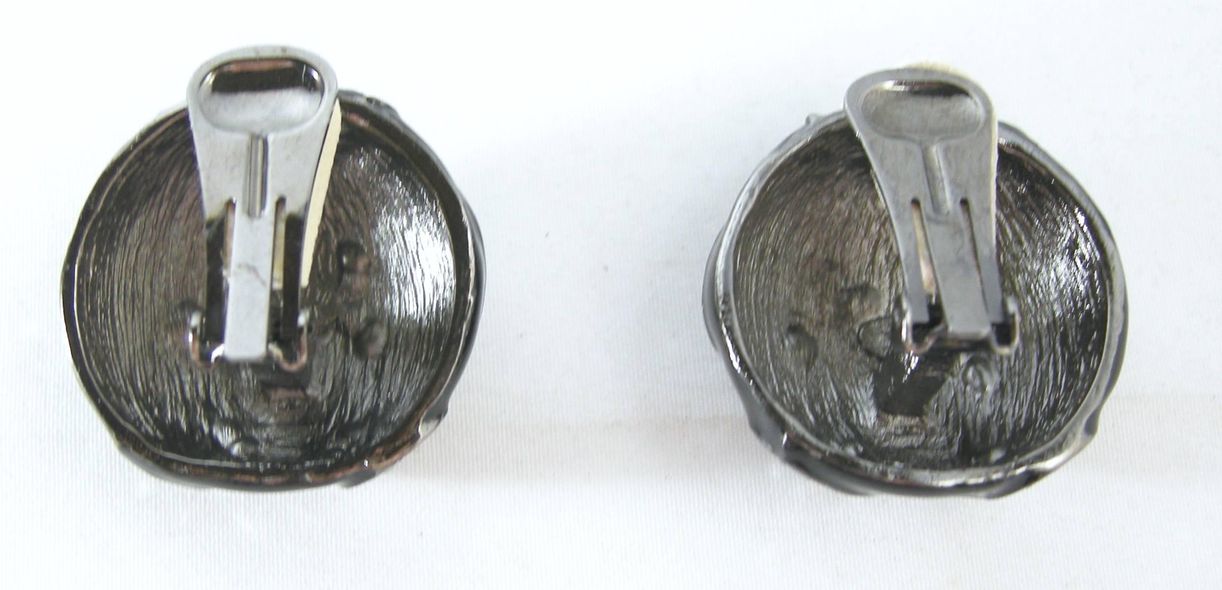 These Kenneth Jay Lane earrings are made with a glossy black enamel with a swirl design of marcasites set in pewter tone finish. They are clip on and measure 1-⅛” x 1-⅛”. They are signed “Kenneth Lane” and are in excellent condition