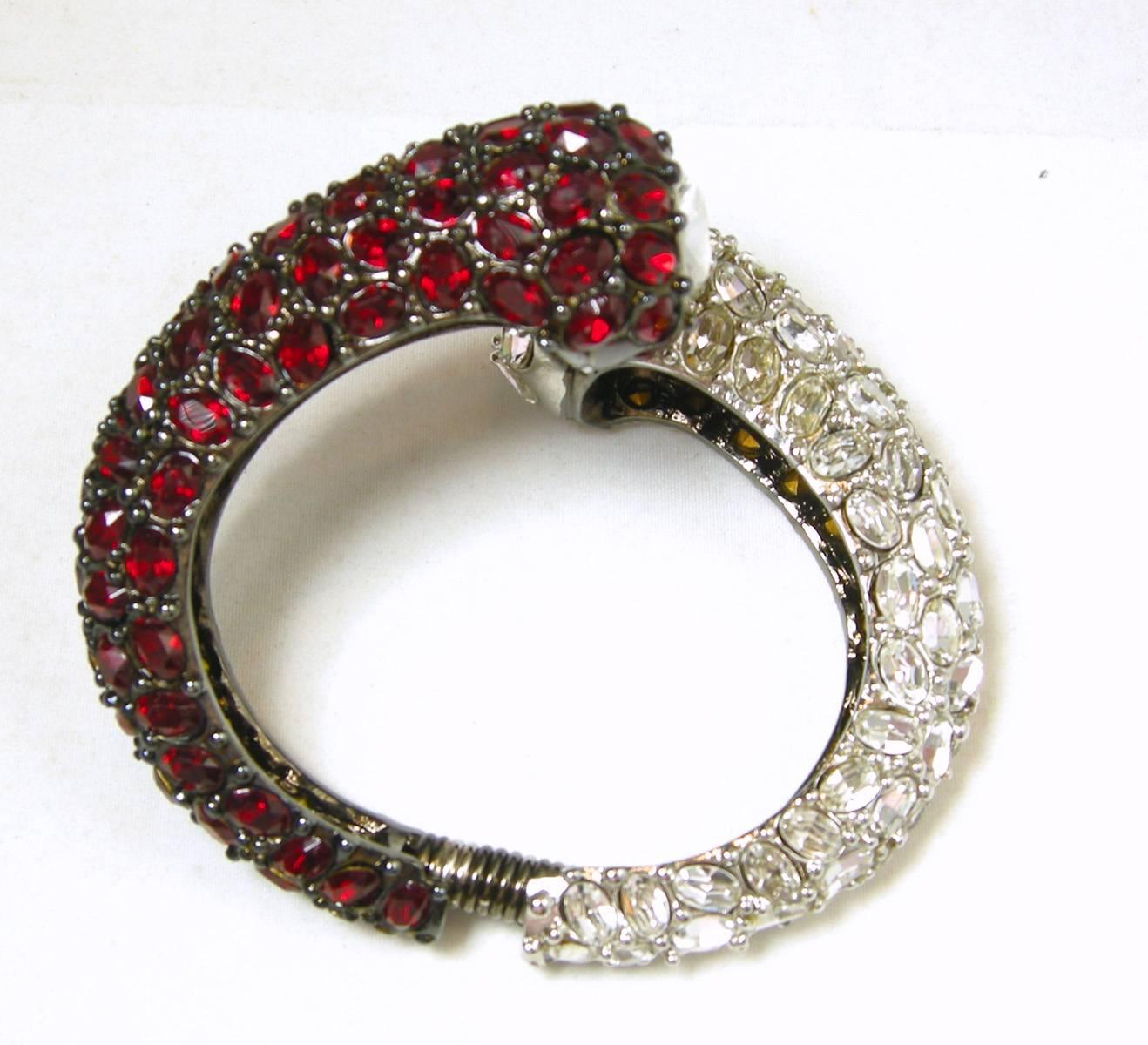 This bracelet is bold with rhinestones.  One half of the bracelet has faux rubies stones while the other half has clear crystals. This dramatic bracelet is 7-½” circumference and the knob is 1” across with a large brilliant crystal. It is in a