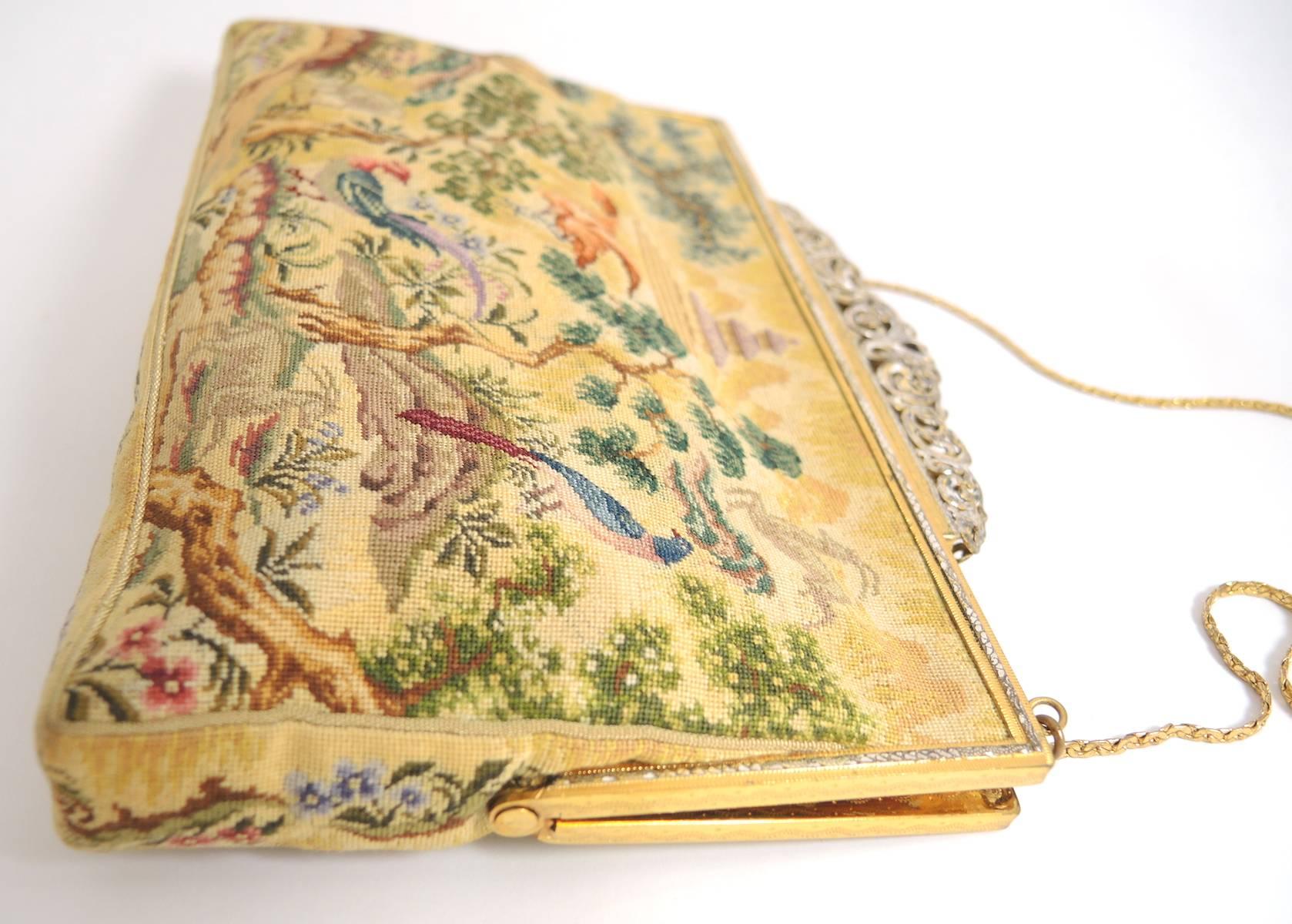 This is a beautiful tapestry handbag with a tiara-style top closure. The tapestry features a garden with trees, birds and an Asian temple on top. The inside has a gold satin lining. It has a gold-tone handle and measures 5-1/2” x 7-3/4”. The handle