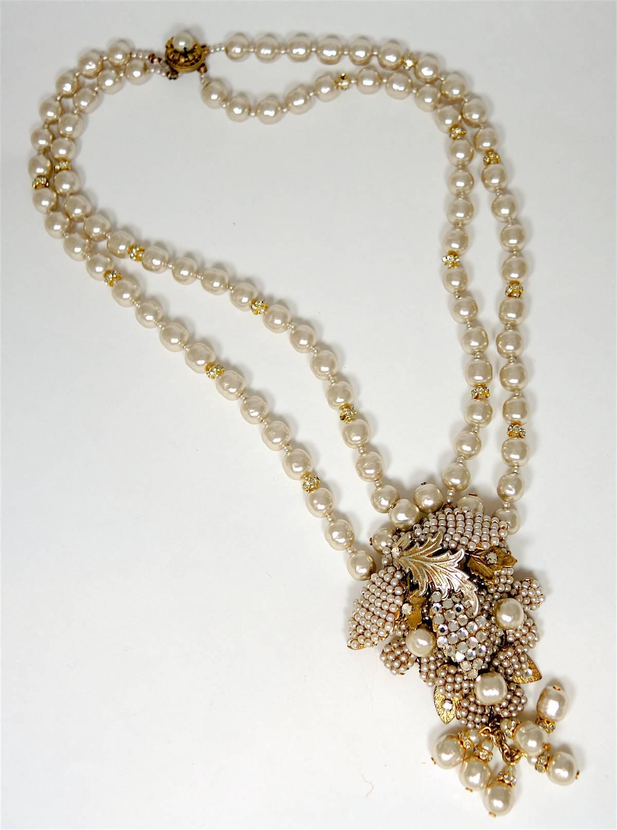 This stunning vintage signed Miriam Haskell necklace features 2-strands of faux pearls leading to a floral centerpiece. This piece has 6 dangling faux pearls at the bottom. This necklace measures 18” x 3/4” and the centerpiece measures 4-1/8” x 2”. 