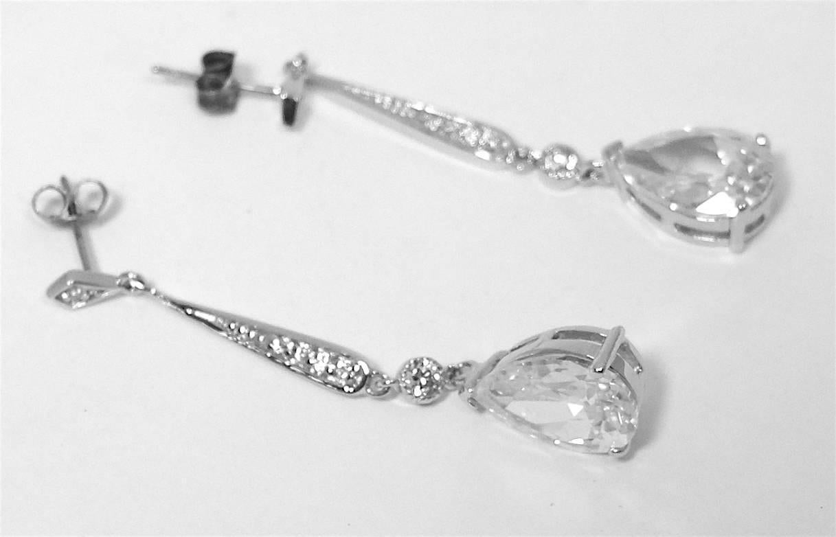 These beautiful dangling earrings are designed with brilliant crystals in a teardrop at the bottom. It is in a sterling silver setting. They are pierced and measure 2” x 1/4” and are in excellent condition. 