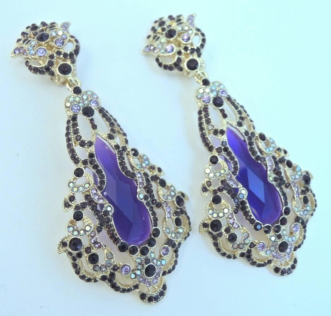These majestic and impossible to find designer chandelier clip earrings have a faux amethyst center stone surrounded with purple and clear crystals. They are in a gold tone setting, measure 3-1/2” x 1-1/8” and are in excellent condition.