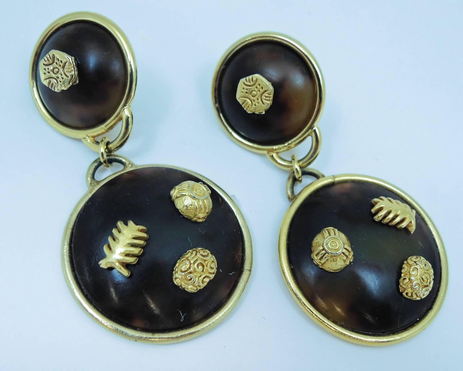 These Dominique Aurientis earrings are amazing! There are two circular faux tortoise shell buttons drops that graduate in size in a gold frame. The buttons have decorative 3-dimensional designs on them. The matching earrings are clip back and