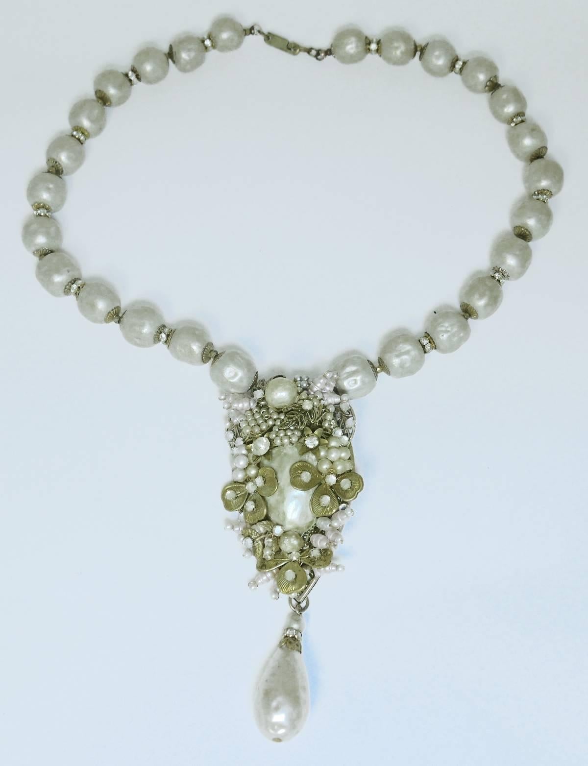 This all original Miriam Haskell necklace is created with large sized cream color faux pearls. Each pearl is spaced with rhondell accents. The teardrop centerpiece is designed with a large faux pearl centerpiece with golden leaves, seed pearls and