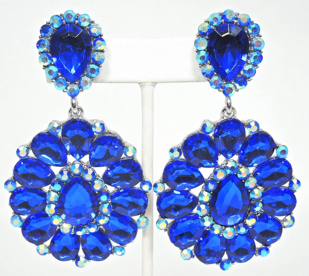 These are a pair of dramatic faux sapphire blue flower clip earrings. They are made with teardrop and round shaped crystals. They are made in a silver tone setting and measure a whopping 3-1/2” x 2”. They are in excellent condition.