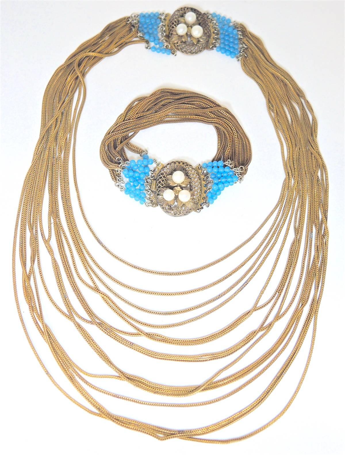 This vintage Victorian necklace is layered with chains that graduate downward.  The necklace is accented with faux turquoise beads on both sides of an oval slide in clasp with 3 faux pearls set on golden leaves. The necklace measures 16” x 1”.  The