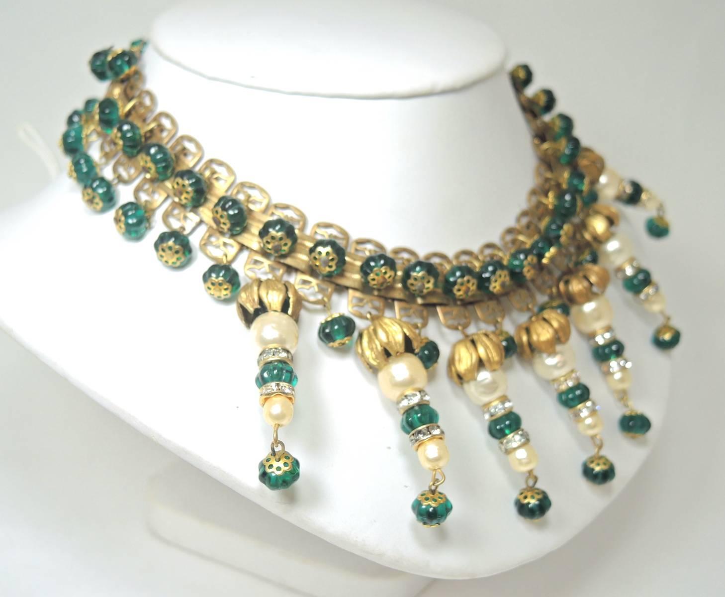 This is a spectacular vintage 1940s French necklace that was made with green Gripoix glass drops. They are spaced by faux pearls and rhondell bead caps. These dangling beauties are connected to a gold tone setting. This necklace measures 16” x 1”. 