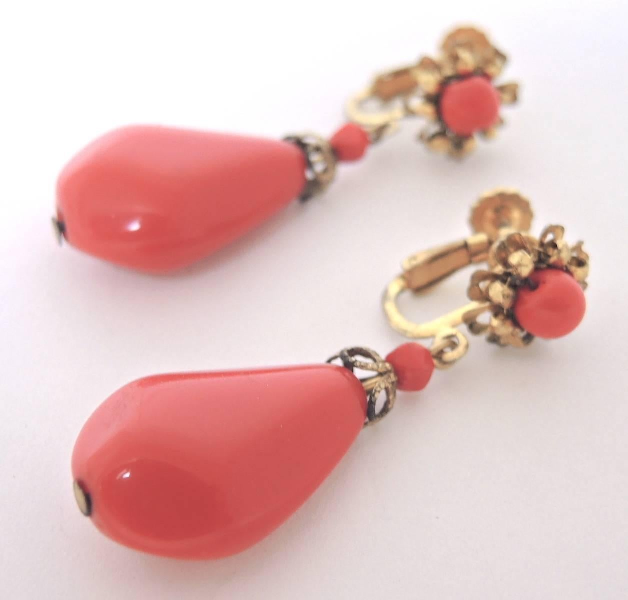 These vintage Miriam Haskell 1950s clip earrings are a perfect accessory to wear any time of the year. These dangling faux coral floral earrings measure 2” x 1/2” and have a gold tone setting. They are signed “Miriam Haskell” and are in excellent