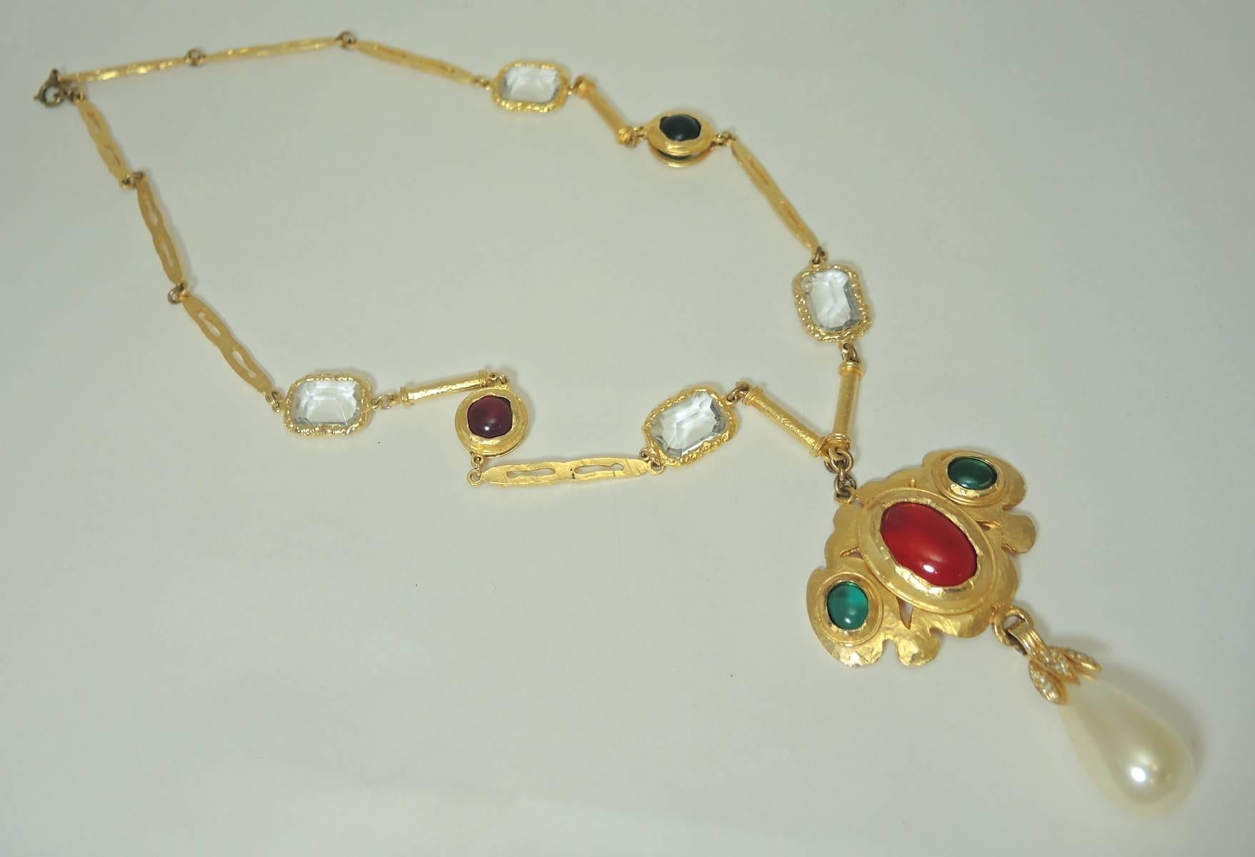 This necklace has red, green and clear faux glass chicklets making the necklace have an almost Chanel look. The centerpiece has a large red cabochon and two smaller green cabochons on each side.  A large dangling teardrop faux pearl hangs at the