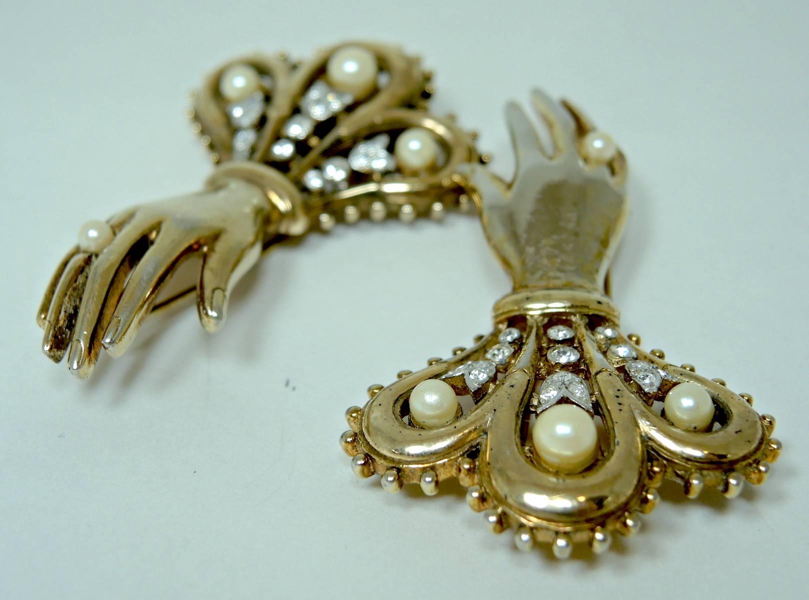 This set of lovely hand fur clips by Trifari was made in the 1940s by Alfred Philippe.  They’re made with sparkling clear rhinestones and faux pearls. It is made in a gold tone setting and measures 2-1/2” x 1-1/2”. It is signed “Trifari” with the