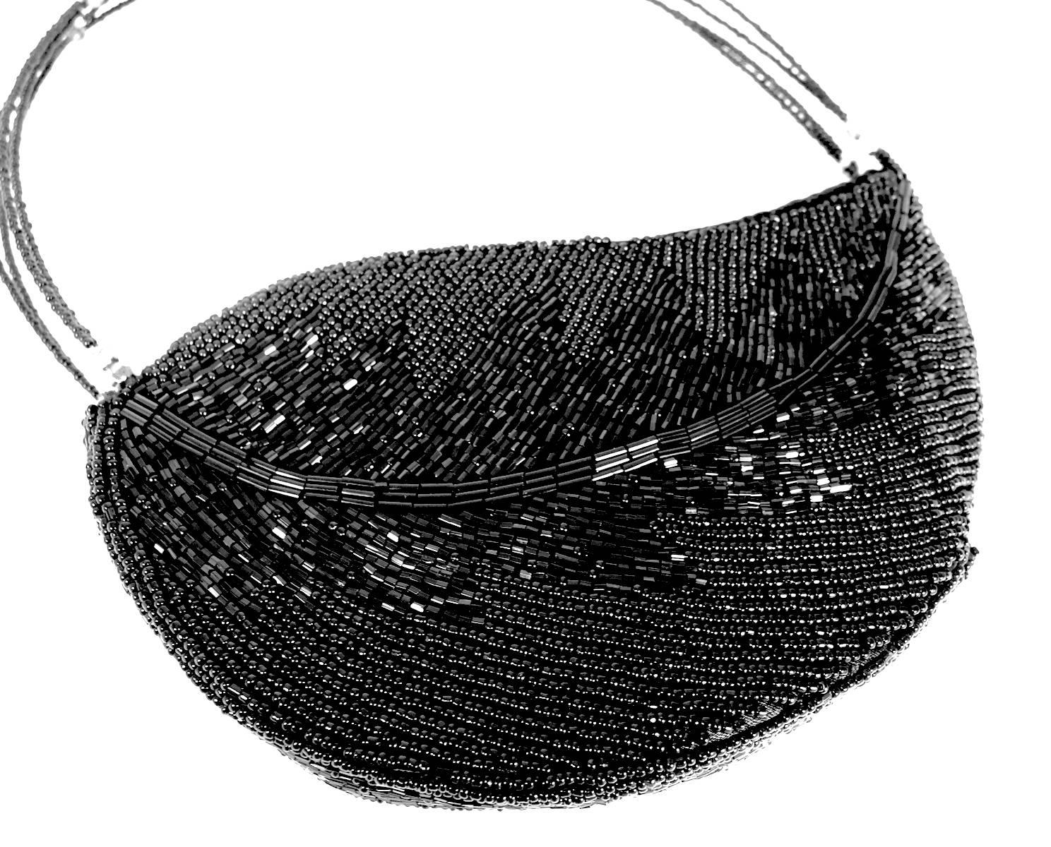 This very elegant leaf shaped handbag is set in dazzling black bugle beads and will make a perfect addition for any occasion. The handles are made with thin wire decorated with bugle beads and Aurora Borealis glass beads. This bag measures 8” x 5”.
