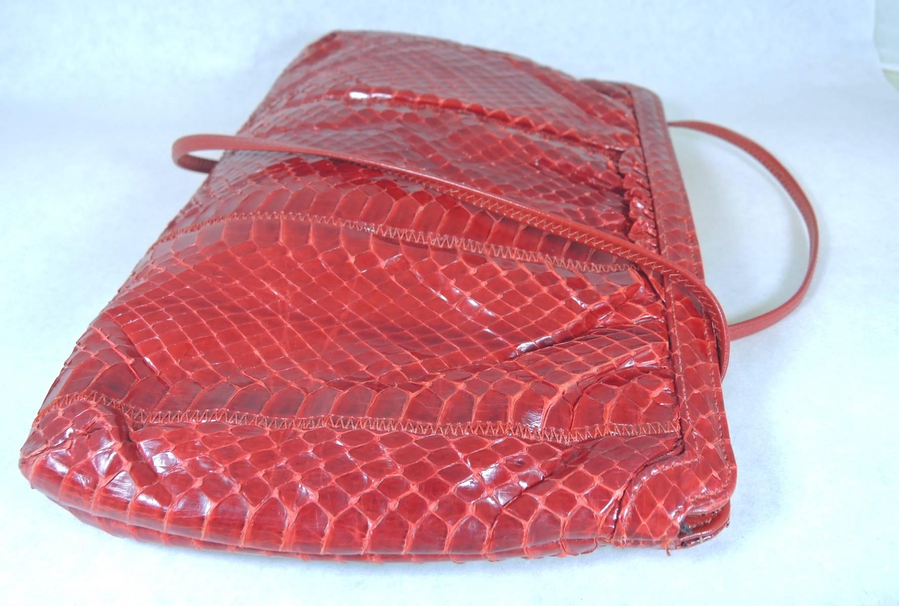 This is a beautiful vintage red shoulder bag that was designed by Palizzio. It has a deep, rich red color in perfect snakeskin leather. It has a metal band that snaps to open and close and has a fabric lining. This bag measures 7” x 10”. The strap