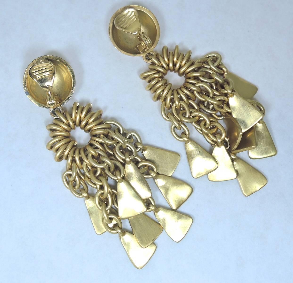 These important, unusual, dramatic French clip earrings are elegant showstoppers!  They are made with a button top and have a cluster of golden chain links that dangle with triangular pendants. These earrings are in a gold tone setting and measure