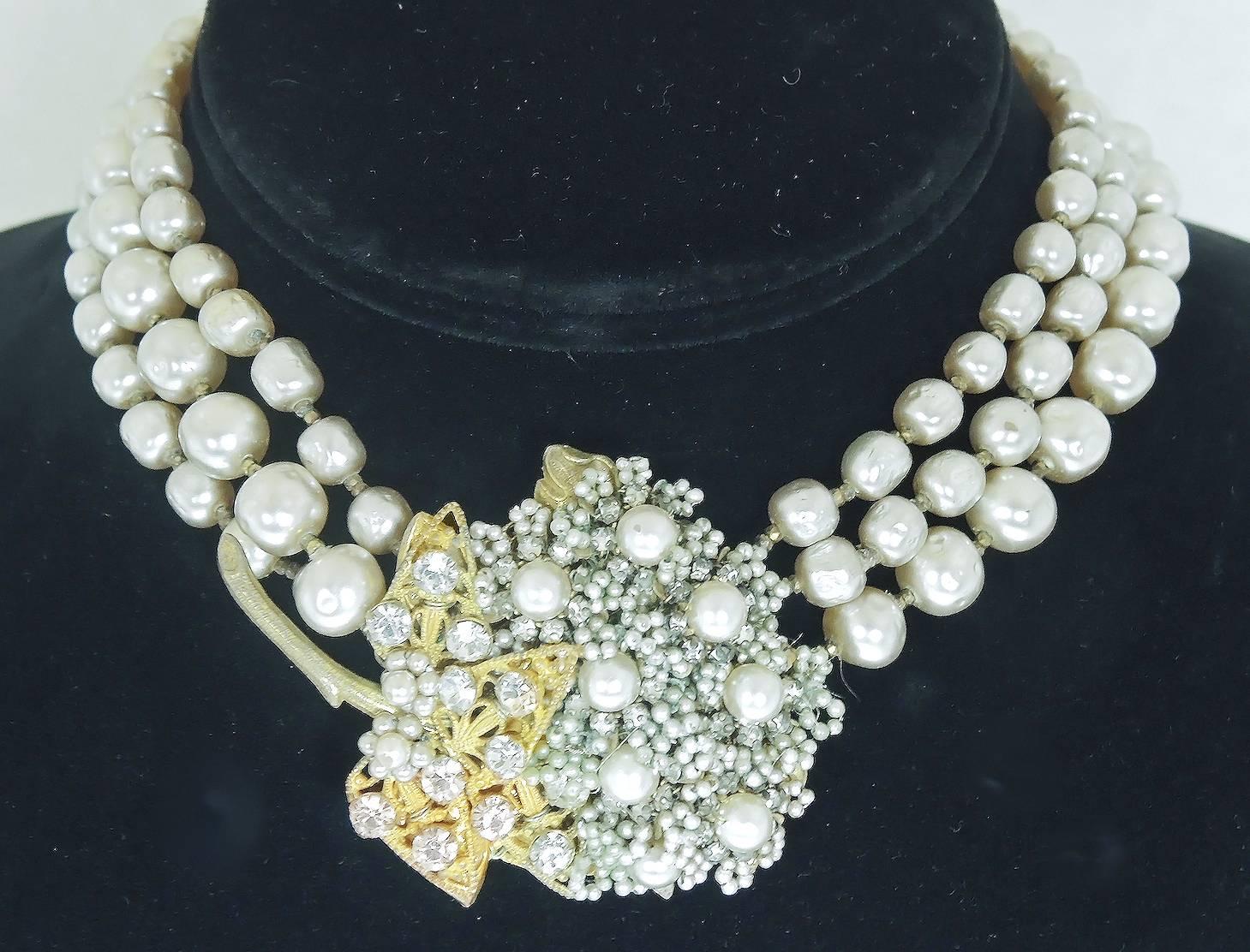 This Miriam Haskell choker features three strands of lustrous cream color baroque pearls that lead to a centerpiece designed with eight pearls and clusters of faux seed pearls. There is a gold tone leaf designed with rose montee and has a very long