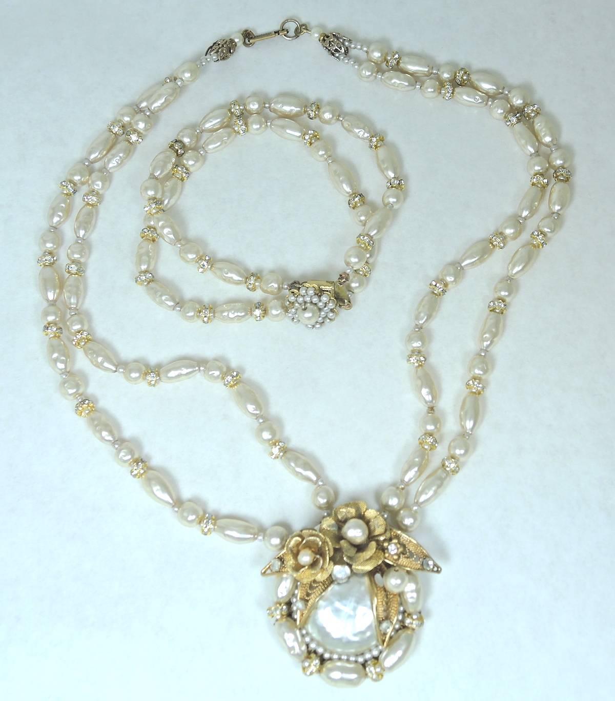 This stunning 1948 Miriam Haskell set features a double strand faux baroque pearls with rhondelle spacers.  It leads downward to a gorgeous centerpiece that has a large faux pearl center with rice pearls on the border and two golden flowers on top.