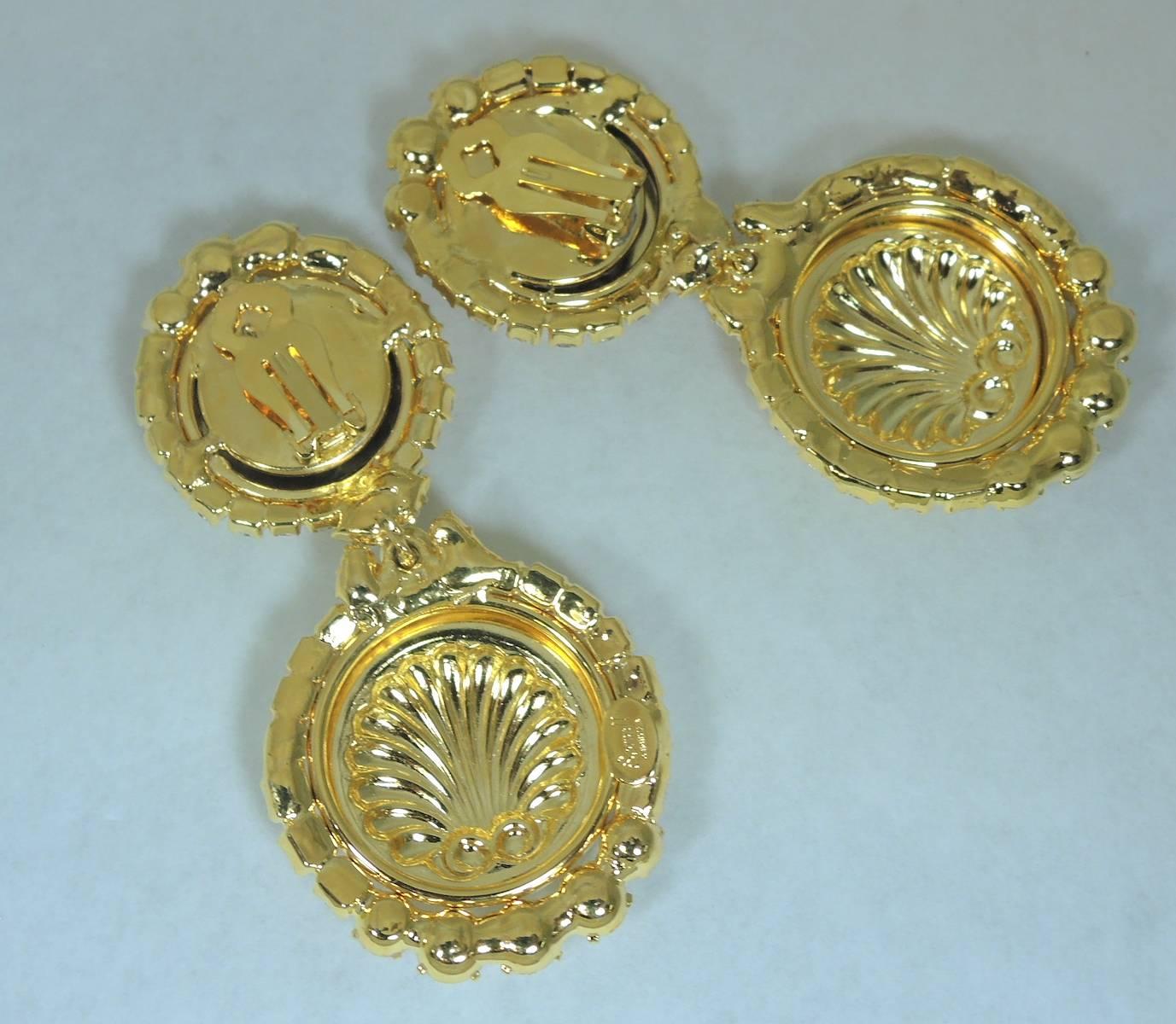 These are a beautiful, one of kind, clip earrings by Robert Sorrell. They feature two circular discs adorned with sparkling crystal accents and seashells. They measure 3-1/2” x 3/8”. They are in a gold tone setting and are signed “Sorrell