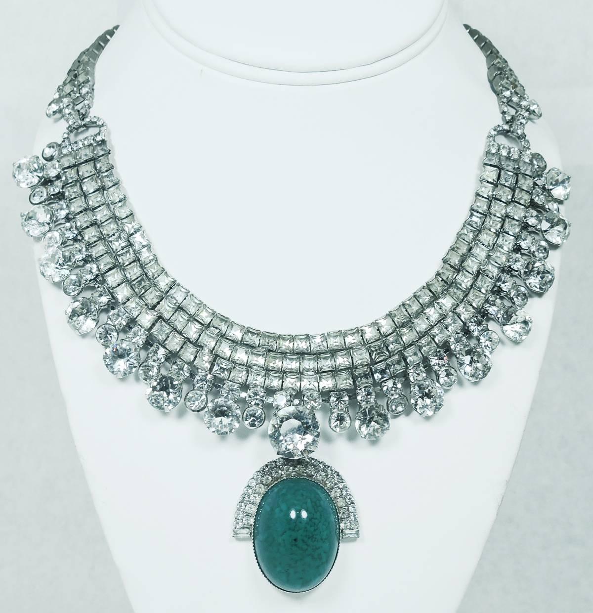 This vintage 1980s stunning, one-of-kind, necklace was made by Robert Sorrell. It was designed with three rows of beautiful squared shaped crystals that lead down to round crystals at the base of the necklace. It has a domed shaped green cabochon