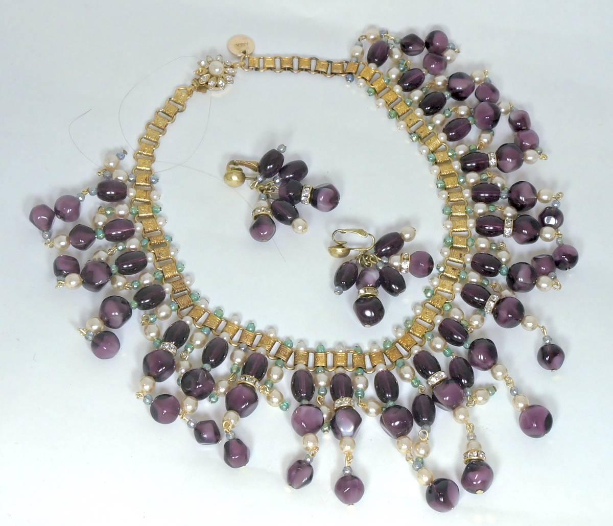 This vintage signed Anka set features faux pearls, bezel cut purple glass beads, and blue tiny beads in a gold tone setting. This necklace measures 16” x 3” and has a slide in clasp. The matching clip earrings measure 2” x 1-1/2”. This set is signed